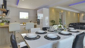 A modern dining area with a white table set for six, surrounded by black leather chairs. - Family Villa With Swimming Pool (Liznjan)