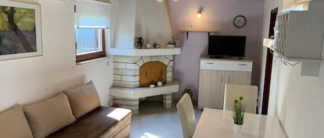 A cozy living area with a sofa, a dining table, a TV, and a fireplace.