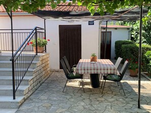 A patio area with a table and chairs, a potted plant, and a staircase leading to a door. - Apartment With one Room Near City Centre (Pula)