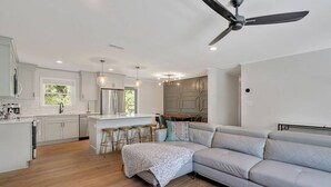 Una cocina moderna con gabinetes blancos, una isla central y taburetes de bar.