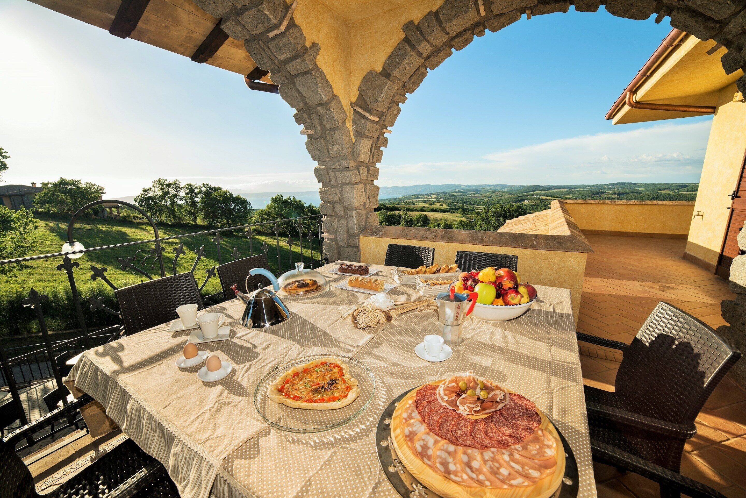An outdoor dining area with a table set for a meal, overlooking a scenic landscape.
