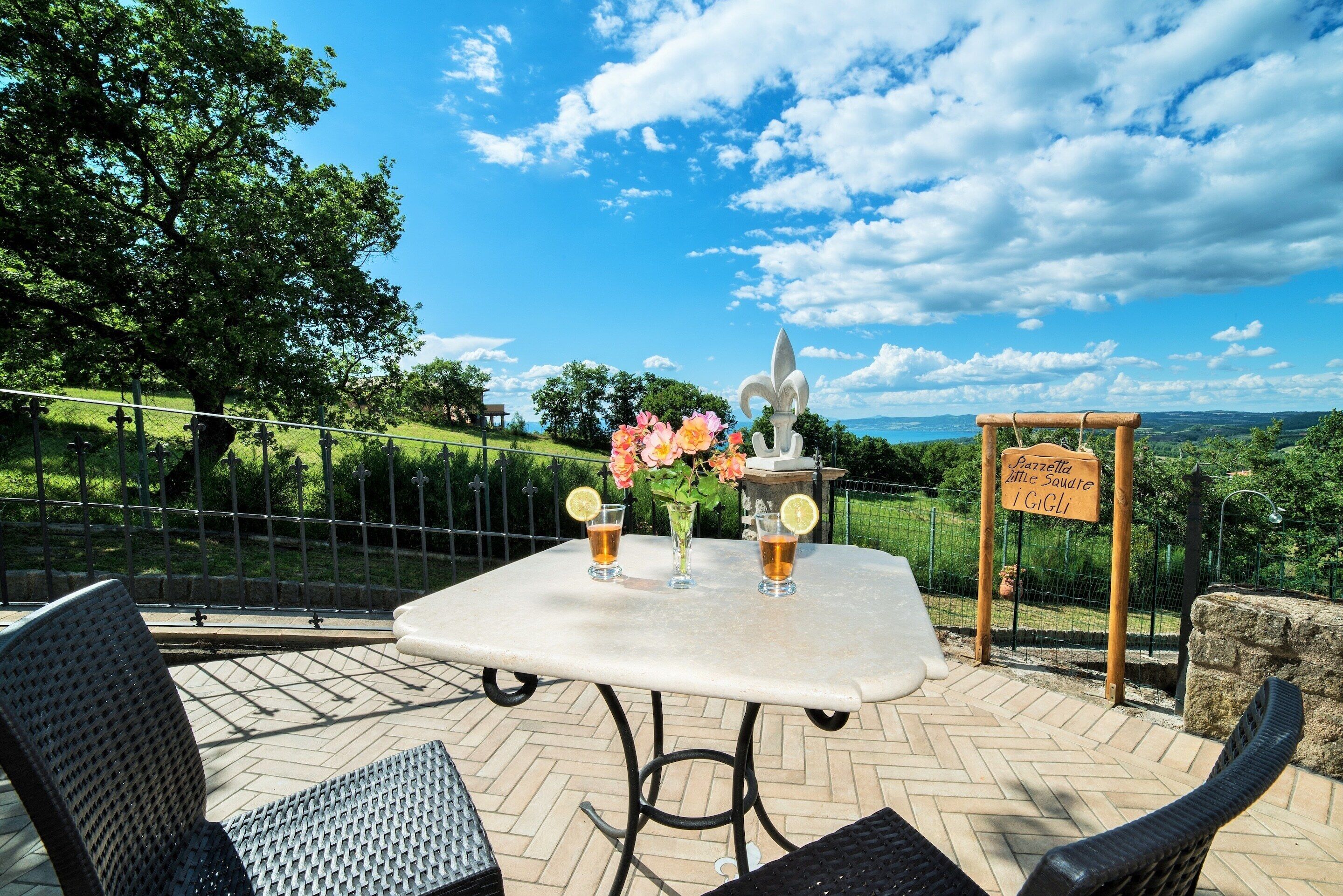 Eine Terrasse im Freien mit einem Tisch für zwei Personen, inklusive einer Vase mit Blumen und zwei Biergläsern.