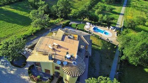 Un edificio amplio de una sola planta con techo de tejas, piscina y jardín bien cuidado.