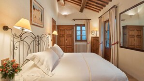 A bedroom with a wooden ceiling, a bed with white linens, a radiator, and a window with curtains. - Charming House in Tuscany With Pool (Umbertide)