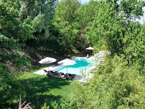 A private pool area with lounge chairs and umbrellas, surrounded by dense greenery. - Charming House in Tuscany With Pool (Umbertide)
