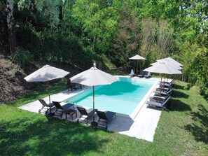 Une piscine rectangulaire avec des chaises longues et des parasols.