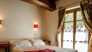 A bedroom with a bed, two bedside tables, a red lamp, and a window with curtains. - Belvilla by OYO Da Pino Bilocale (Marsciano)