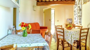 A dining area with a table set for two, a vase of flowers, and a television on a side table. - Belvilla by OYO Da Pino Bilocale (Marsciano)