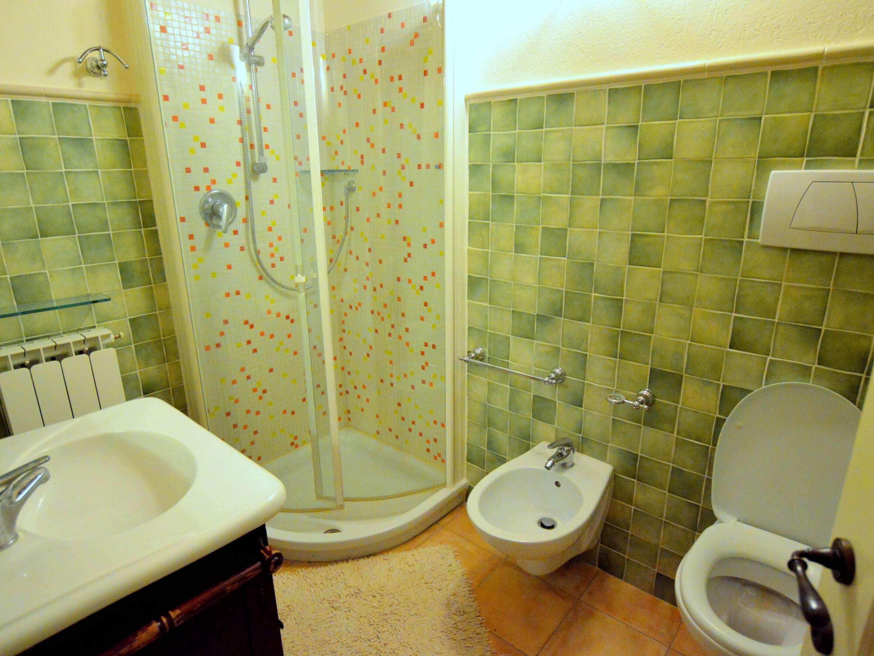 A bathroom with a shower, bidet, toilet, and sink.