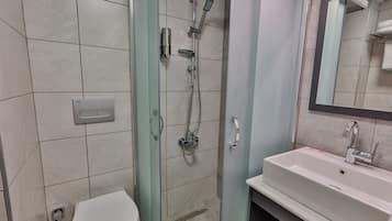 A bathroom with a shower, toilet, sink, and mirror.