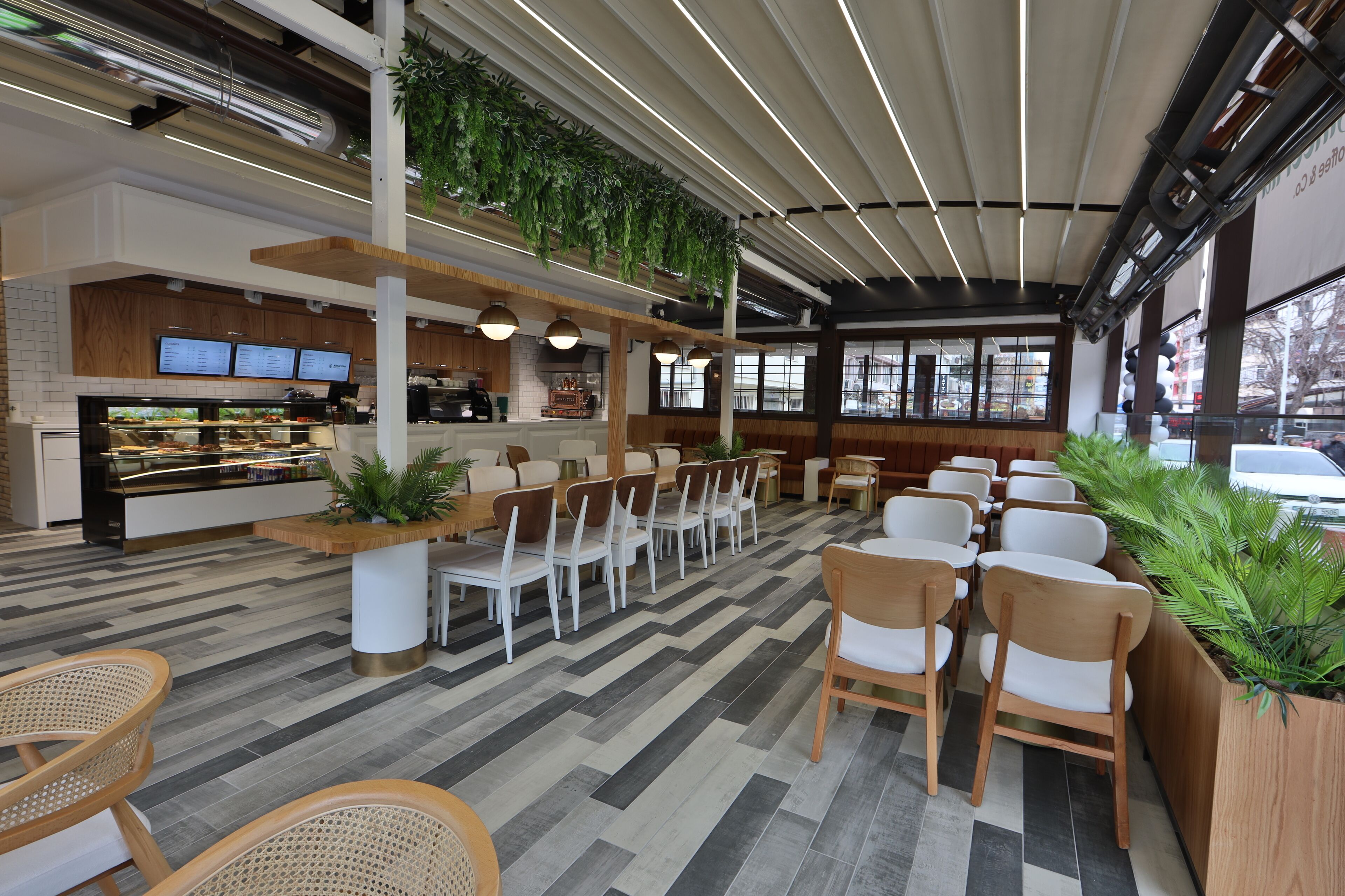 A modern restaurant with a long counter, white chairs, and a herringbone-patterned floor.