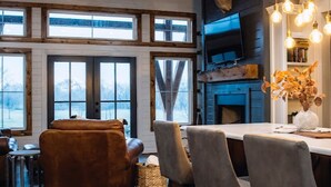 A cozy interior with a wooden dining area, a fireplace, and a television mounted on the wall.