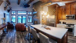 A modern kitchen with a central island, wooden cabinets, and stainless steel appliances.