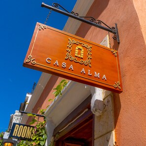 A sign for "CASA ALMA" with a decorative emblem, hanging from a metal fixture. - Hotel Casa Alma (Cartagena)