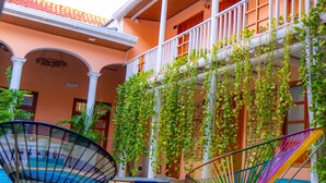 Ein Innenhof mit Pool, Sitzgelegenheiten im Freien und einem Balkon mit Pflanzen.
