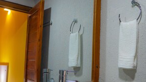 Ein Badezimmer mit einem weißen Waschbecken, einem Spiegel und einem Holzschrank.