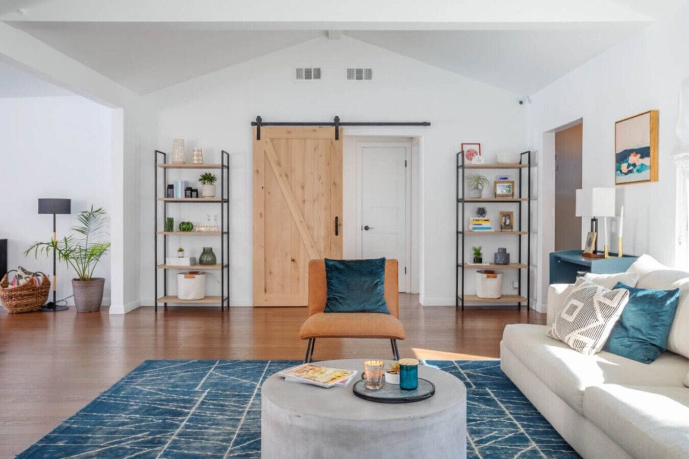A modern living room with a sofa, armchair, coffee table, and bookshelves.