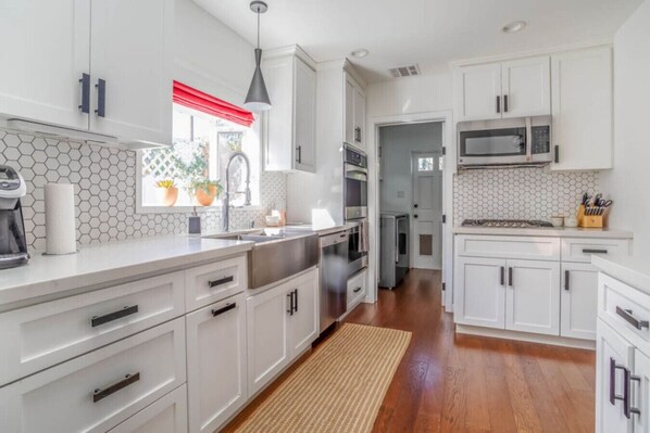 A modern kitchen with white cabinetry, a stainless steel sink, and a microwave.