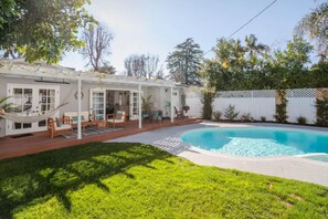 A backyard with a swimming pool, a hammock, and outdoor furniture.