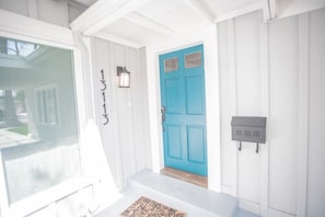 A front entrance with a blue door, a mailbox, and a number sign.