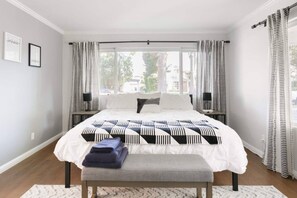 A bedroom with a large bed, a bench, and a view of the outdoors.
