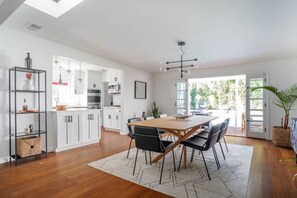 A modern kitchen with white cabinets, a wooden dining table, and black chairs.