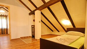 A bedroom with a wooden floor, a bed with a green mattress, and a sloped ceiling with exposed beams. - Apartments Lemes - Comfort One Bedroom Apartment With Garden View (Janjina)