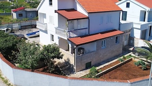 A two-story building with a red-tiled roof, white exterior walls, and a balcony on the upper floor. - Apartments Lemes - Comfort One Bedroom Apartment With Garden View (Janjina)