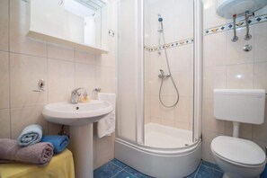 Une salle de bain équipée d’une douche, de toilettes, d’un lavabo et de serviettes.