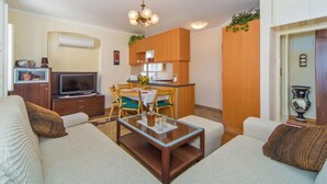 Un espace de vie compact comprenant un canapé, une table basse et un petit coin cuisine avec des meubles en bois et une table à manger.
