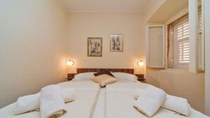 Un lit double avec deux serviettes blanches, une tête de lit en bois et deux lampes fixées au mur.