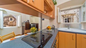 Une cuisine moderne dotée d’une plaque de cuisson à induction intégrée, de meubles en bois et d’un mur de crédence en pierre.