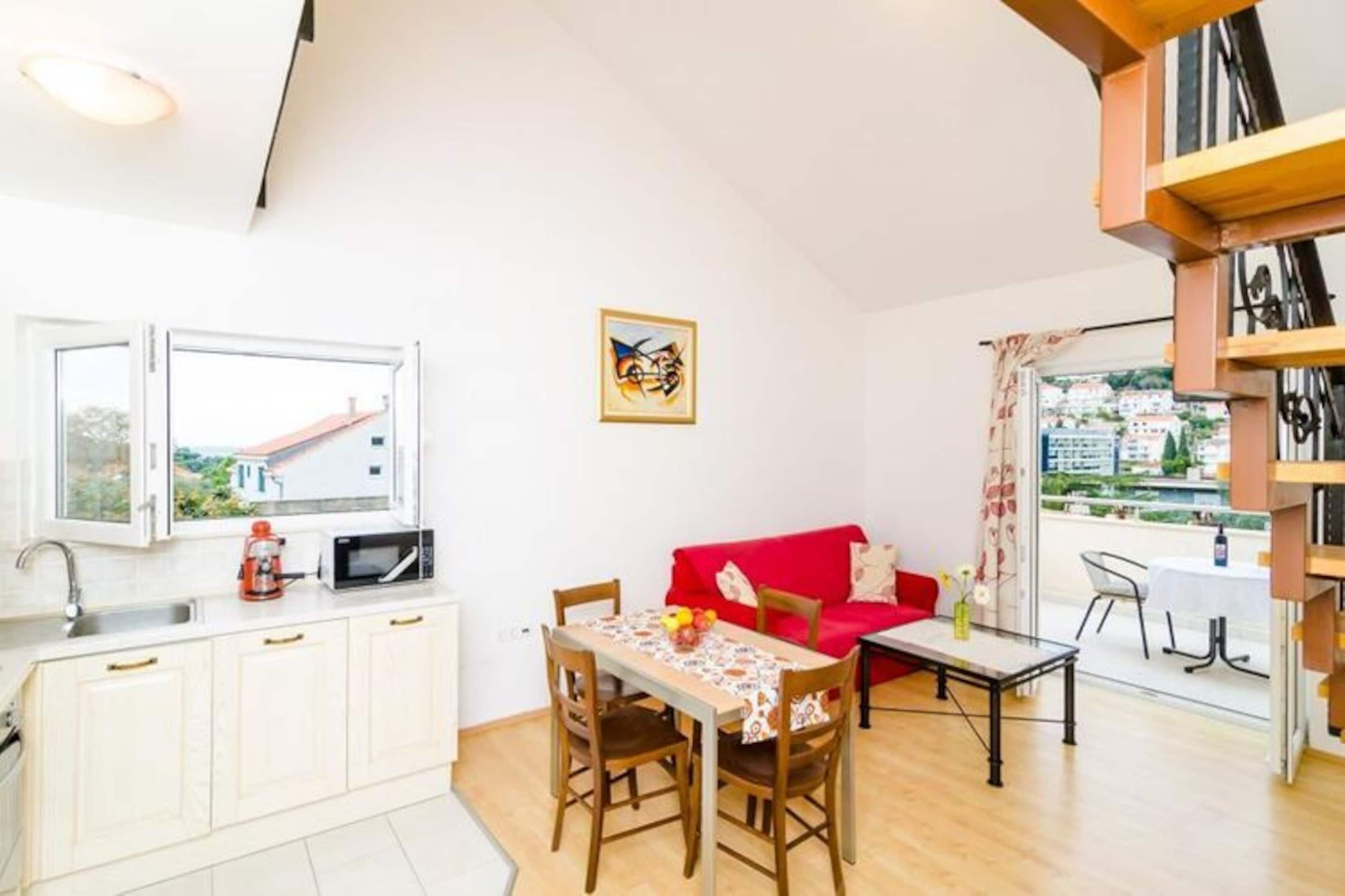 A compact living space with a kitchenette, dining area, and a red sofa.