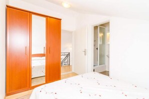 A bedroom with a bed, a wardrobe, and a bathroom visible through an open door. - Apartments Nikola - Superior One Bedroom Apartment With Sea View (Dubrovnik)
