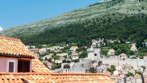 A historic town with a prominent castle on a hill, surrounded by residential buildings with red-tiled roofs. - Apartment Taura - Studio Apartment With Balcony and Old City View (Dubrovnik)