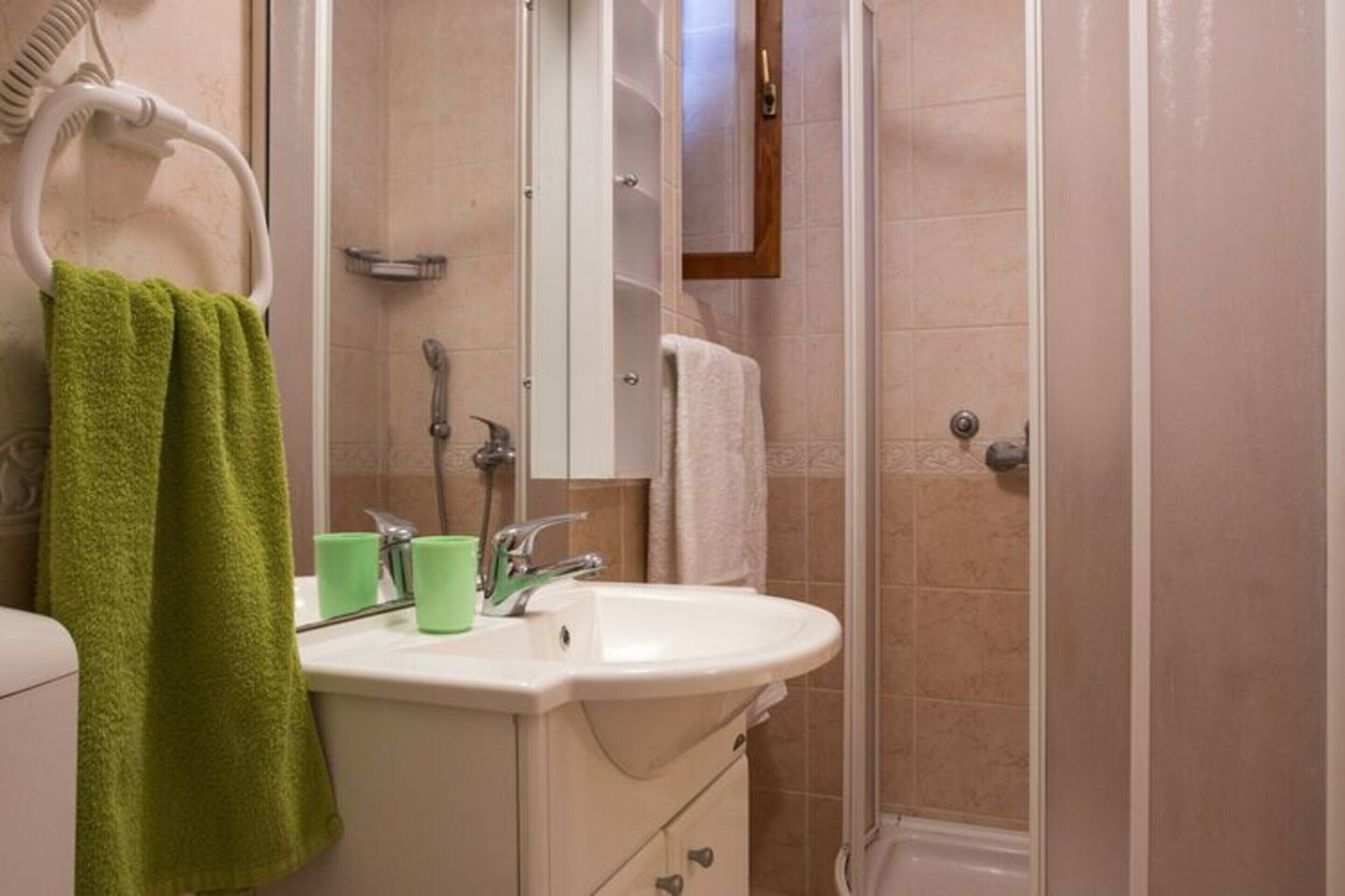 A bathroom with a sink, mirror, towel rack, and shower.