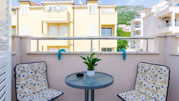 Ein Balkon mit zwei Stühlen, einem kleinen Tisch und einem Blumentopf.