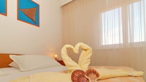 Ein Hotelzimmer mit Bett, Nachttisch, Lampe und zwei gerahmten Kunstwerken an der Wand.