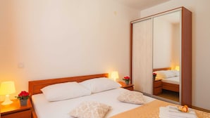 Une chambre d’hôtel avec un lit, des lampes de chevet, un miroir et une petite table sur laquelle est posé un vase avec des fleurs.