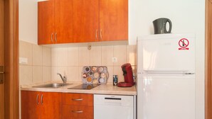 Une cuisine avec des meubles de rangement en bois, un évier, une machine à café et un réfrigérateur blanc.