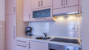 A modern kitchen with white cabinets, a stainless steel sink, a built-in microwave, and an oven. - Apartment in Medulin With Balconies (Medulin)