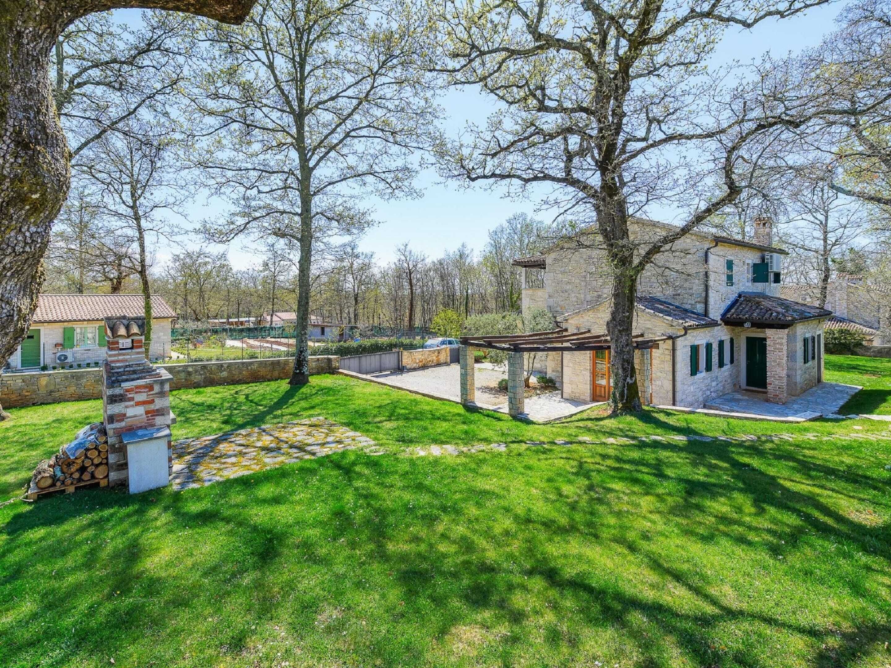 Un bâtiment en pierre avec un toit en tuiles, entouré d’une pelouse bien entretenue et d’arbres.