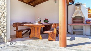 An outdoor patio with a wooden table and benches, a stone floor, and a stone oven. - Apartment in Liznjan With Pool and Terrace (Liznjan)