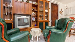 A living room with green leather armchairs, a wooden cabinet with glass doors, and a television. - Apartment in Liznjan With Pool and Terrace (Liznjan)