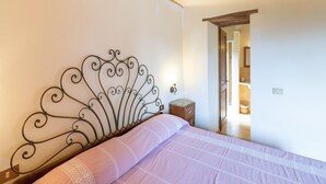 Une chambre avec une tête de lit en métal, un lit avec une literie rose, une table de chevet et un plafond en bois.