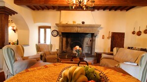 Una sala de estar acogedora con chimenea, dos sillones y una mesa de comedor con un centro de frutas.