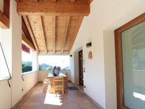 A covered patio with a wooden table and chairs, a view of the outdoors, and a door leading to another room. - Belvilla by OYO Riva dei Tor (Miane)