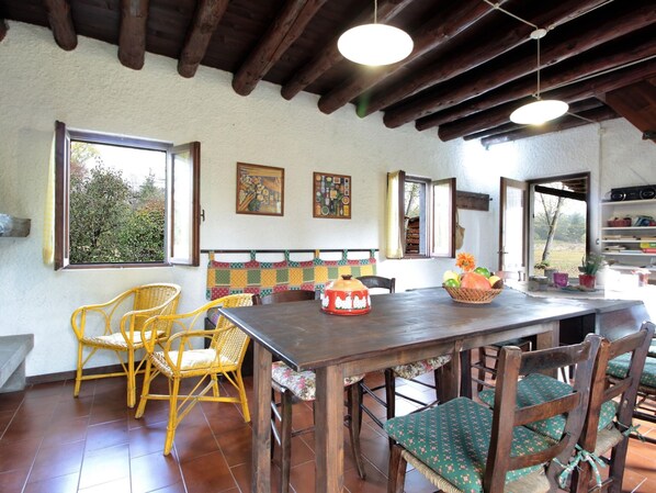 A rustic dining area with a wooden table, wicker chairs, and a bench.