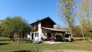 A two-story wooden house with a balcony, surrounded by trees and a grassy area. - Mountain Hideaway for Four (Santa Giustina)