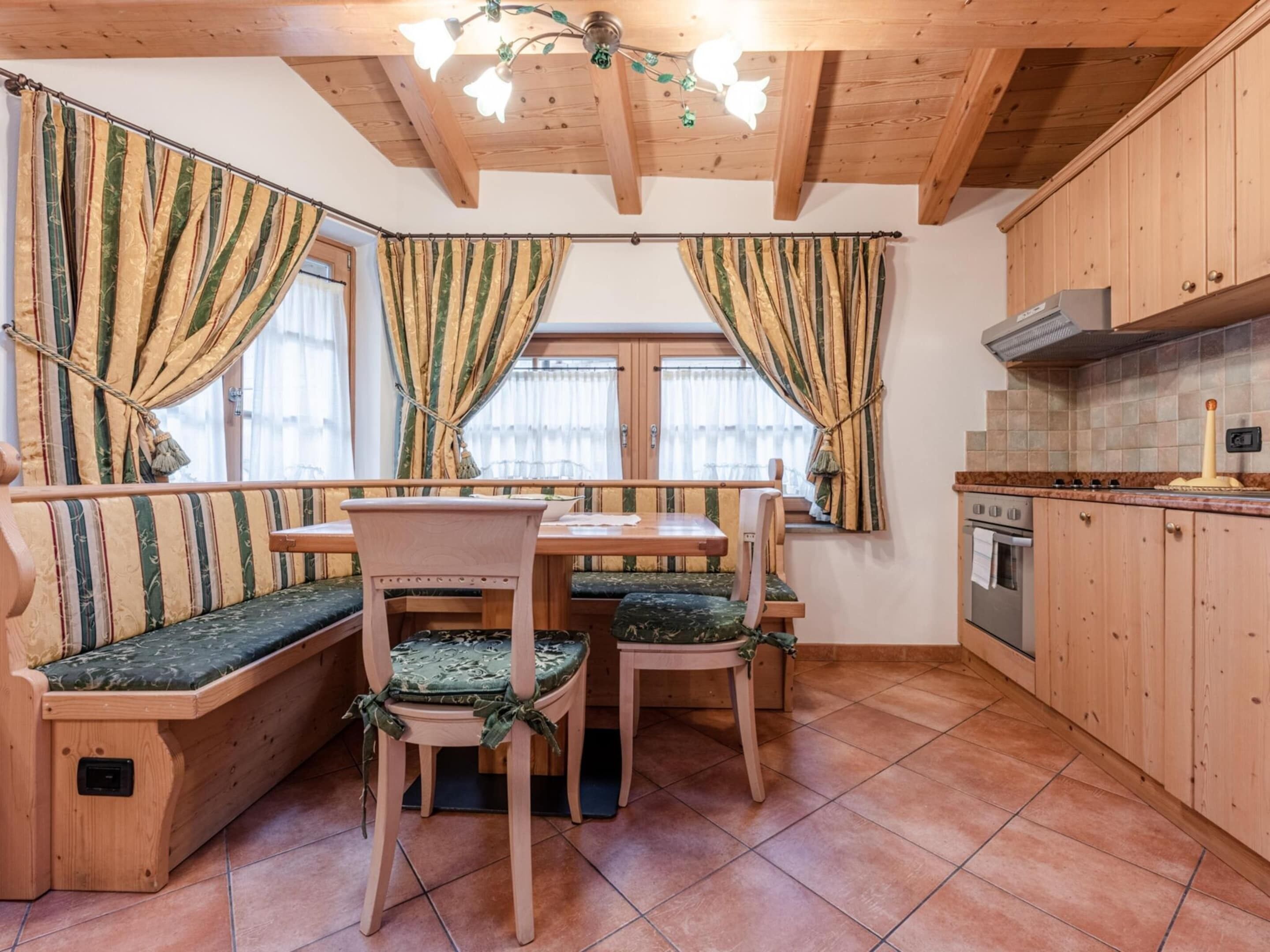 Una cocina acogedora con armarios de madera, una mesa de comedor con bancos y un banco empotrado con cojines.